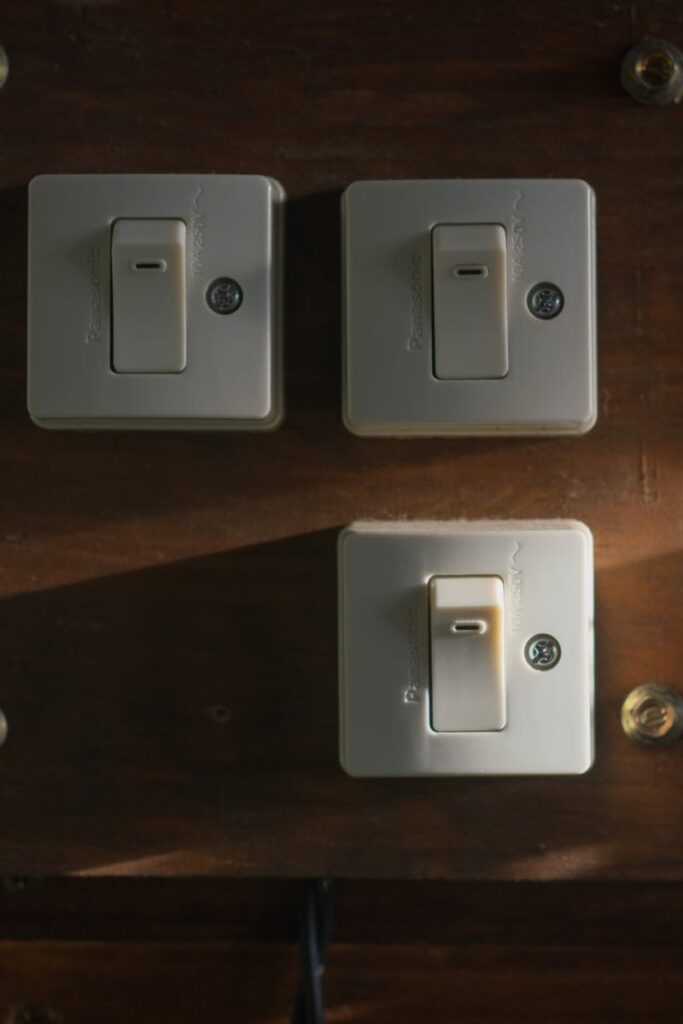 Close-up view of vintage light switches mounted on a wooden panel, illuminated softly in a dark interior setting.